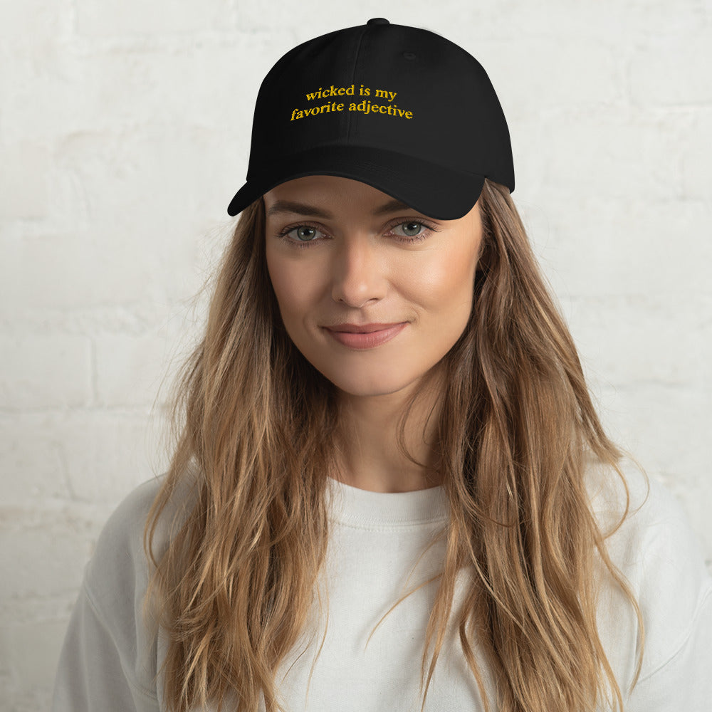 woman wearing black hat that says "wicked is my favorite adjective" in gold embroidery