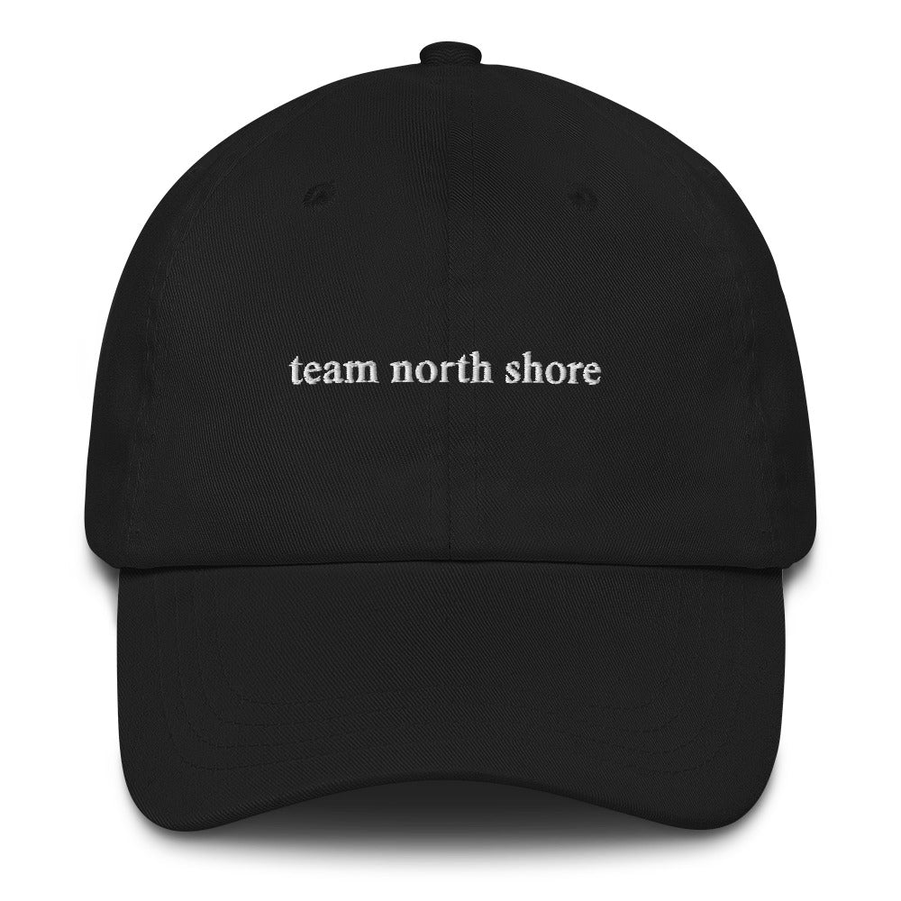 black baseball hat that says "team north shore" in white lettering