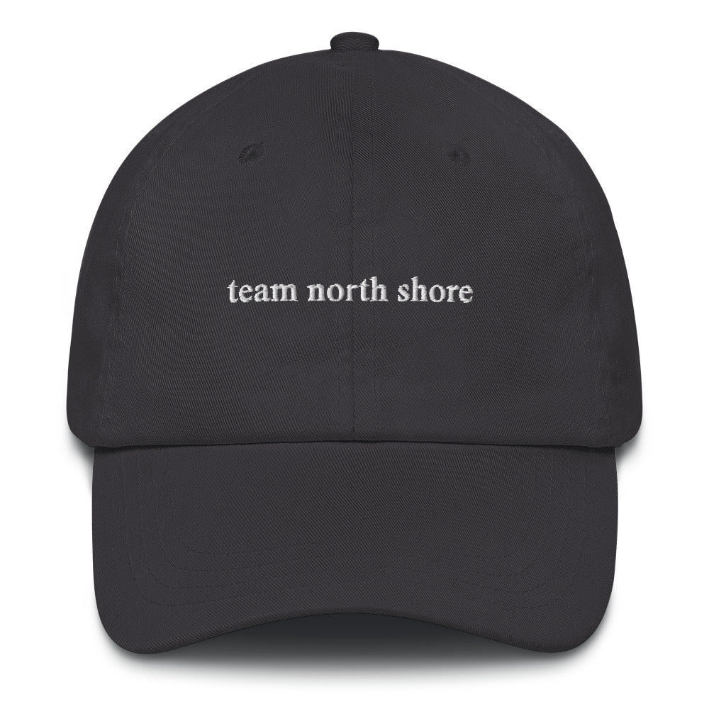 dark grey baseball hat that says "team north shore" in white lettering