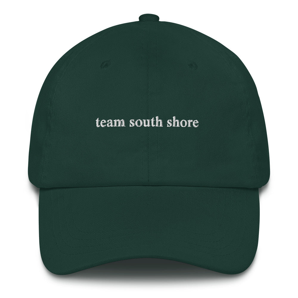 green baseball hat that says "team south shore" in white lettering