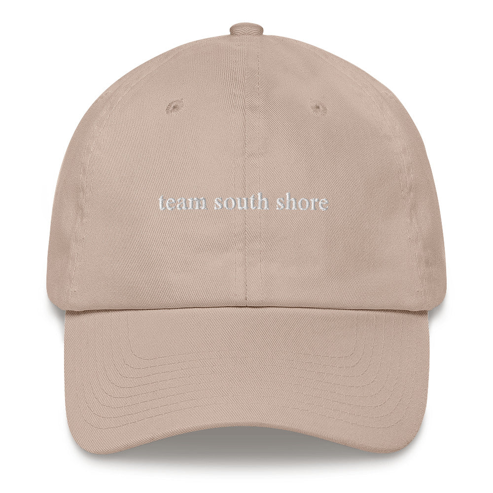 tan baseball hat that says "team south shore" in white lettering