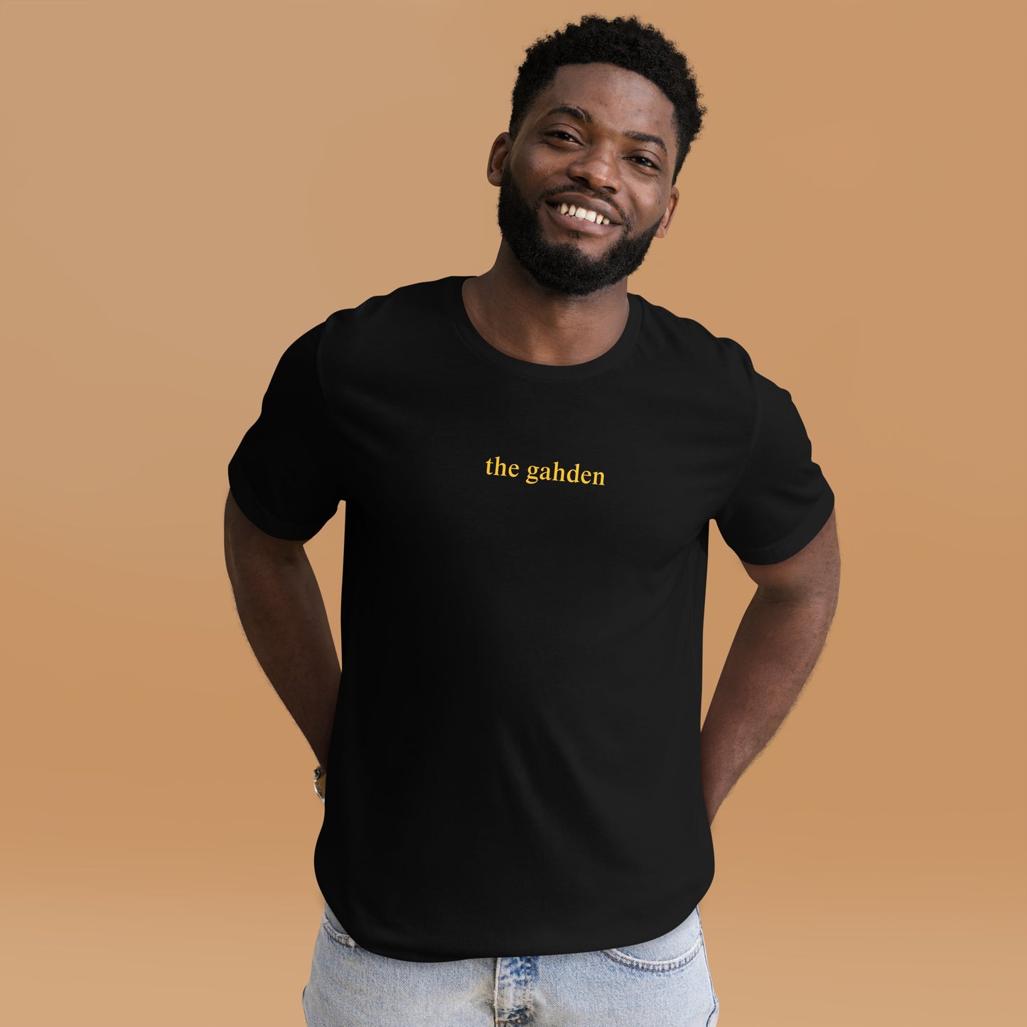 man wearing. black tshirt that says "the gahden" in gold lettering